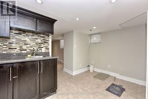 Toronto (Dovercourt-Wallace Emerson-Junction) apartment for rent - A kitchen with dark wood cabinets and a stone backsplash.