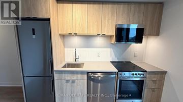 Toronto (High Park North) condo for rent - A kitchen with wooden cabinets and a black fridge.