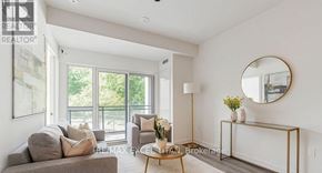 Toronto (Stonegate-Queensway) condo for rent - A living room with a grey couch, a coffee table, and a round mirror on the wall.