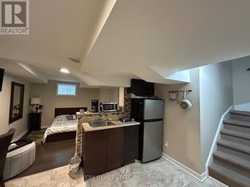 Mississauga (Churchill Meadows) apartment for rent - A kitchen area with a sink, refrigerator, and a bedroom with a bed and a window.
