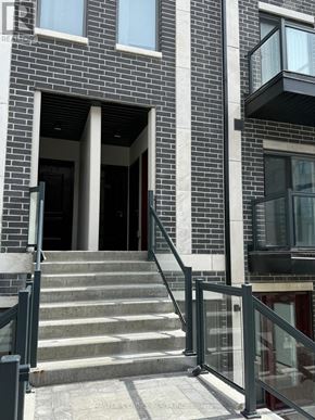Toronto (Tam O'shanter-Sullivan) townhouse for rent - A building with a black and white facade has a set of stairs leading to a doorway.
