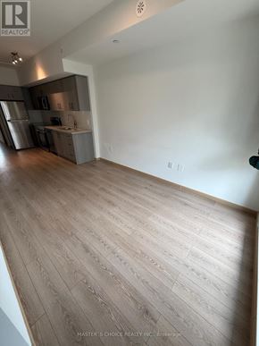 Toronto (Tam O'shanter-Sullivan) townhouse for rent - A spacious room with wooden flooring and a kitchen area in the background.