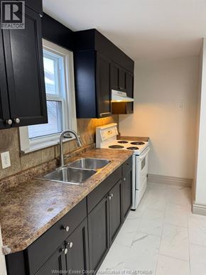 Windsor apartment for rent - A kitchen with black cabinets and a white stove top oven.