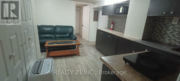 Toronto (Clairlea-Birchmount) apartment for rent - A black leather sofa sits in a kitchen with a wooden coffee table in front of it.