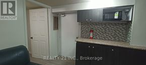 Toronto (Clairlea-Birchmount) apartment for rent - A small kitchen with a black counter top and a white door.