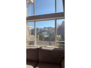 Richmond apartment for rent - A couch is in front of a window with a view of a house and trees.