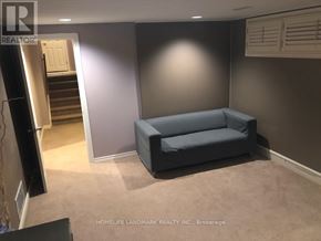 Toronto (Bayview Village) apartment for rent - A living room with a grey couch and a staircase in the background.