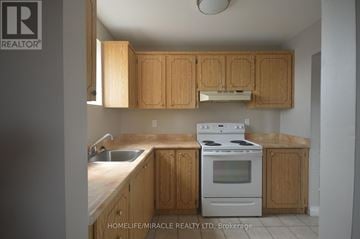 Bradford West Gwillimbury (Bradford) apartment for rent - A kitchen with wooden cabinets and a white stove top oven.