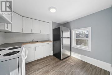 Orillia multi-family for rent - A kitchen with white cabinets and a black refrigerator.