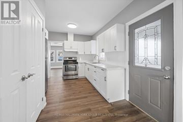 Orillia duplex for rent - A kitchen with white cabinets and a grey door.
