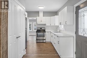 Orillia duplex for rent - A white kitchen with a stove top oven and a sink.