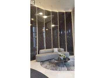 Vancouver apartment for rent - A modern living room with a grey sofa and a glass table.