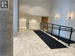 Kitchener condo for rent - A hallway with a marble floor and a black railing.