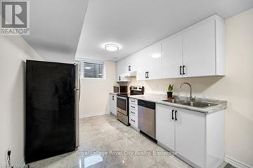 Guelph (Grange Road) apartment for rent - A kitchen with white cabinets and a black refrigerator.