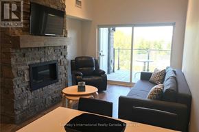 Blue Mountains condo for rent - A living room with a stone fireplace and a flat screen TV mounted above it.