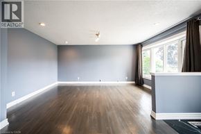 Kitchener apartment for rent - A spacious room with wooden flooring and a large window.