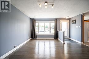 Kitchener apartment for rent - A spacious room with a large window and wooden flooring.