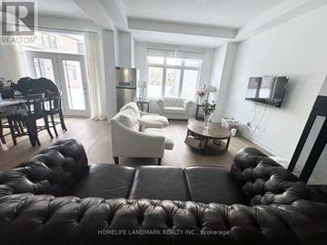 Oakville (Jm Joshua Meadows) apartment for rent - A living room with a black leather couch and a television on the wall.