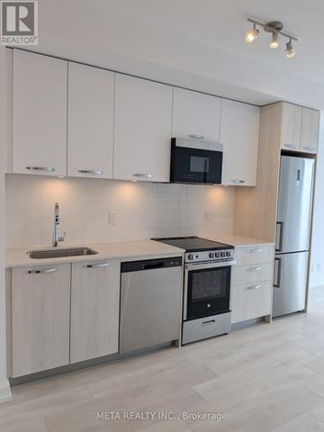 Hamilton (Corktown) condo for rent - A modern kitchen with white cabinets and stainless steel appliances.