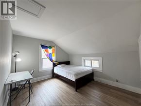 Windsor apartment for rent - A bedroom with a bed, table, and two windows.