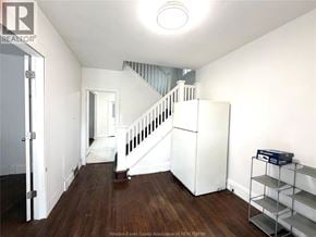 Windsor apartment for rent - A white refrigerator sits in a room with wood floors and a staircase in the background.