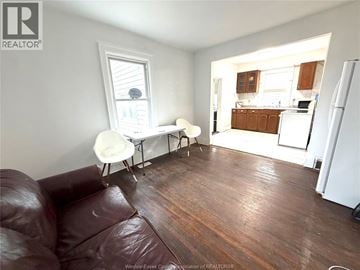 Windsor apartment for rent - A brown leather couch sits in a living room with a dining area in the background.