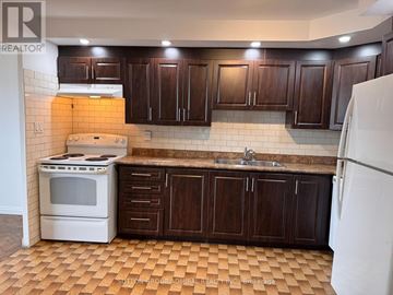 Toronto (Flemingdon Park) condo for rent - A kitchen with brown cabinets and a white stove.