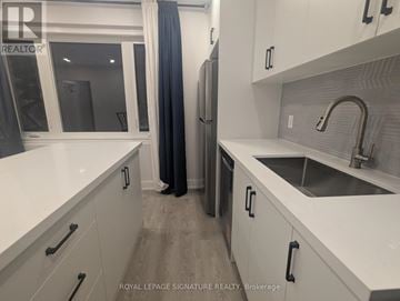 Toronto (Rexdale-Kipling) triplex for rent - A modern kitchen with white cabinets and a stainless steel sink.