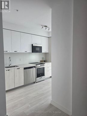 Hamilton (Corktown) condo for rent - A modern kitchen with white cabinets and stainless steel appliances.
