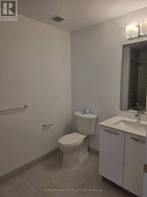 Hamilton (Corktown) condo for rent - A white toilet sits next to a sink in a small bathroom.