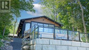 Tiny apartment for rent - A house with a glass balcony is surrounded by trees.