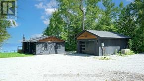 Tiny apartment for rent - Two buildings are situated in a gravel lot with trees in the background.