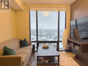 Waterloo condo for rent - A living room with a couch, a coffee table, and a large window overlooking a cityscape.