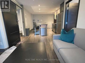 Waterloo condo for rent - A modern kitchen with black appliances and a dining area with a table and chairs.