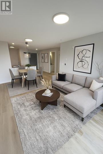 Guelph (Grange Road) condo for rent - A modern living room with a grey sofa, a coffee table, and a dining table set up.