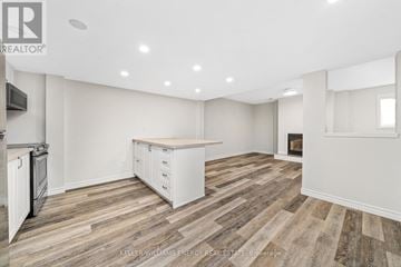 Prince Edward County (Wellington Ward) apartment for rent - A spacious kitchen with white cabinets and a wooden floor.