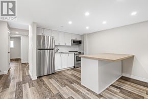 Prince Edward County (Wellington Ward) apartment for rent - A kitchen with a white refrigerator, stove, and oven, and a wooden island in the middle.