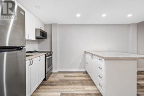 Prince Edward County (Wellington Ward) apartment for rent - A kitchen with white cabinets and a stainless steel refrigerator.