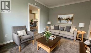 Windsor apartment for rent - A living room with a grey couch, a grey armchair, a wooden coffee table, and a painting on the wall.