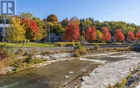 Port Hope apartment for rent - A river flows through a rocky bed with autumn trees in the background.