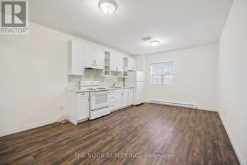 Port Hope apartment for rent - A kitchen with white cabinets and a wooden floor.