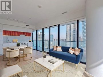 Toronto (Mount Pleasant West) condo for rent - A living room with a blue couch and a table with a vase on it.