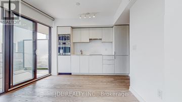 Toronto (Bay Street Corridor) condo for rent - A modern kitchen with white cabinets and a wooden floor.