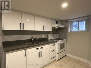 Toronto (Trinity-Bellwoods) townhouse for rent - A kitchen with white cabinets and a black countertop.
