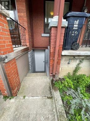 Toronto (Trinity-Bellwoods) townhouse for rent - A small door is on the side of a brick building.