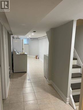 Toronto (Trinity-Bellwoods) townhouse for rent - A hallway with a staircase and a refrigerator in the background.