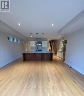 Ottawa apartment for rent - A spacious room with wooden flooring and a kitchen area in the background.