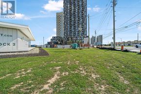 Vaughan (Concord) condo for rent - A grassy area with a building in the background and a sign that says "T.COM STOCK 2".
