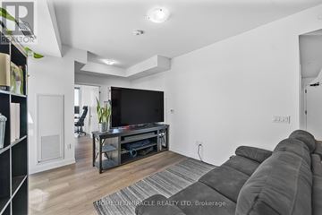 Vaughan (Concord) condo for rent - A living room with a grey sofa and a black entertainment center.