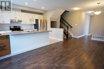 Ottawa townhouse for rent - A kitchen with wooden floors and white cabinets.